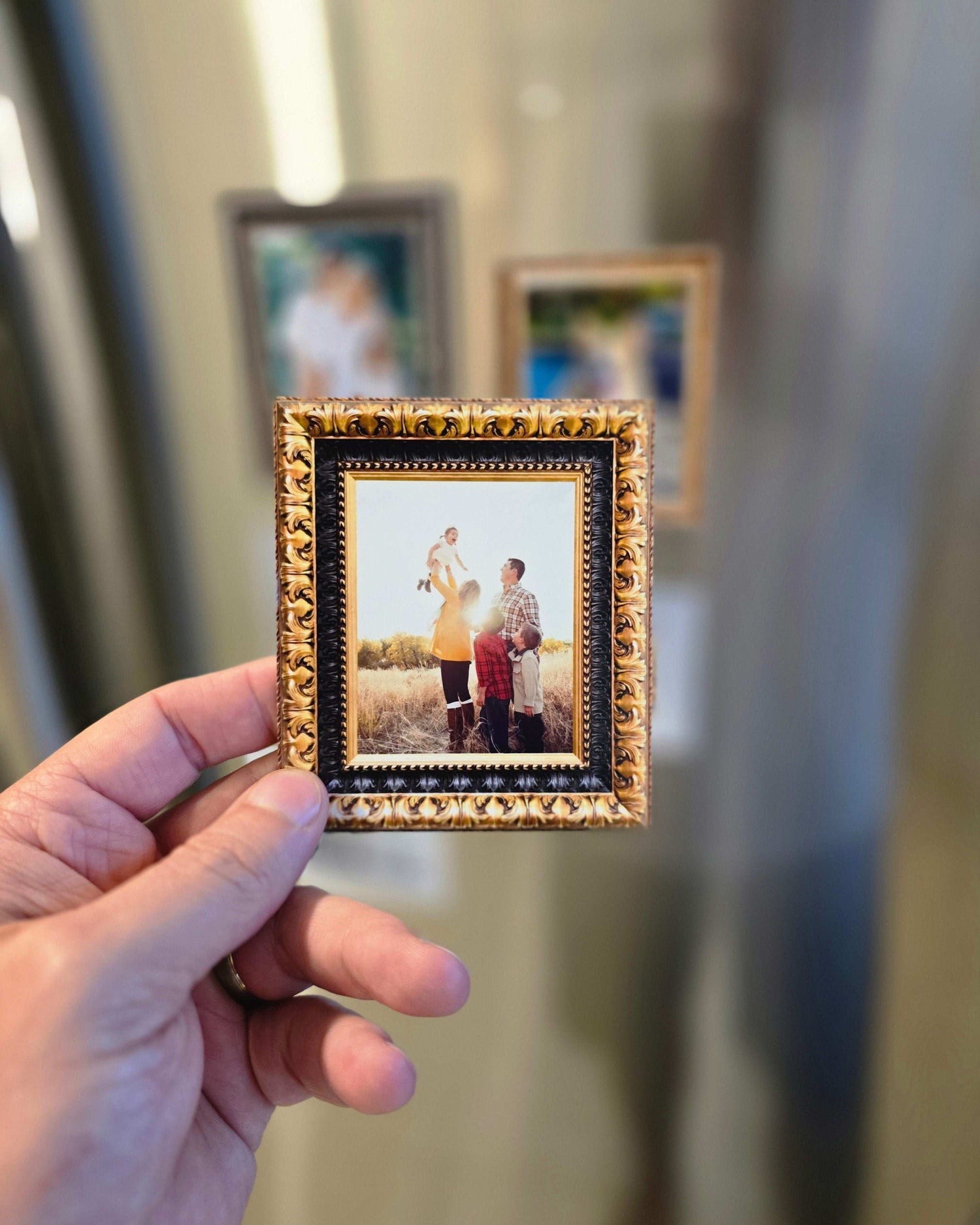 Hand holding a small gold-framed photo  magnet