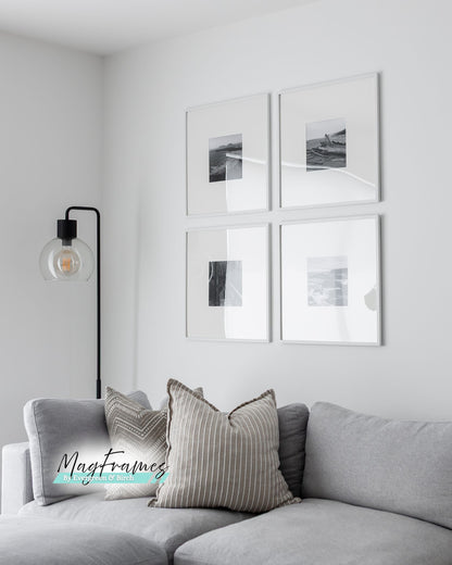 Four 20x20 white MagFrames with plexiglass displayed above a gray sofa in a clean modern living room.