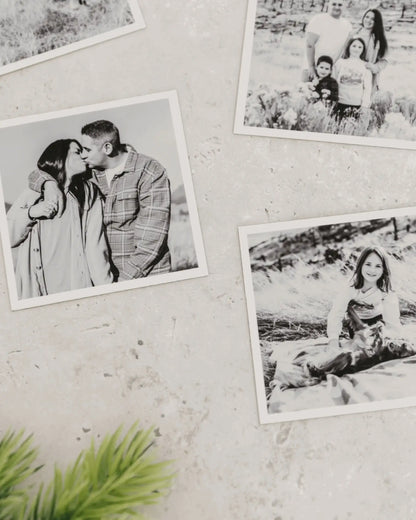 Close-up of black and white custom photo magnets with matte finish displayed on a light textured wall.