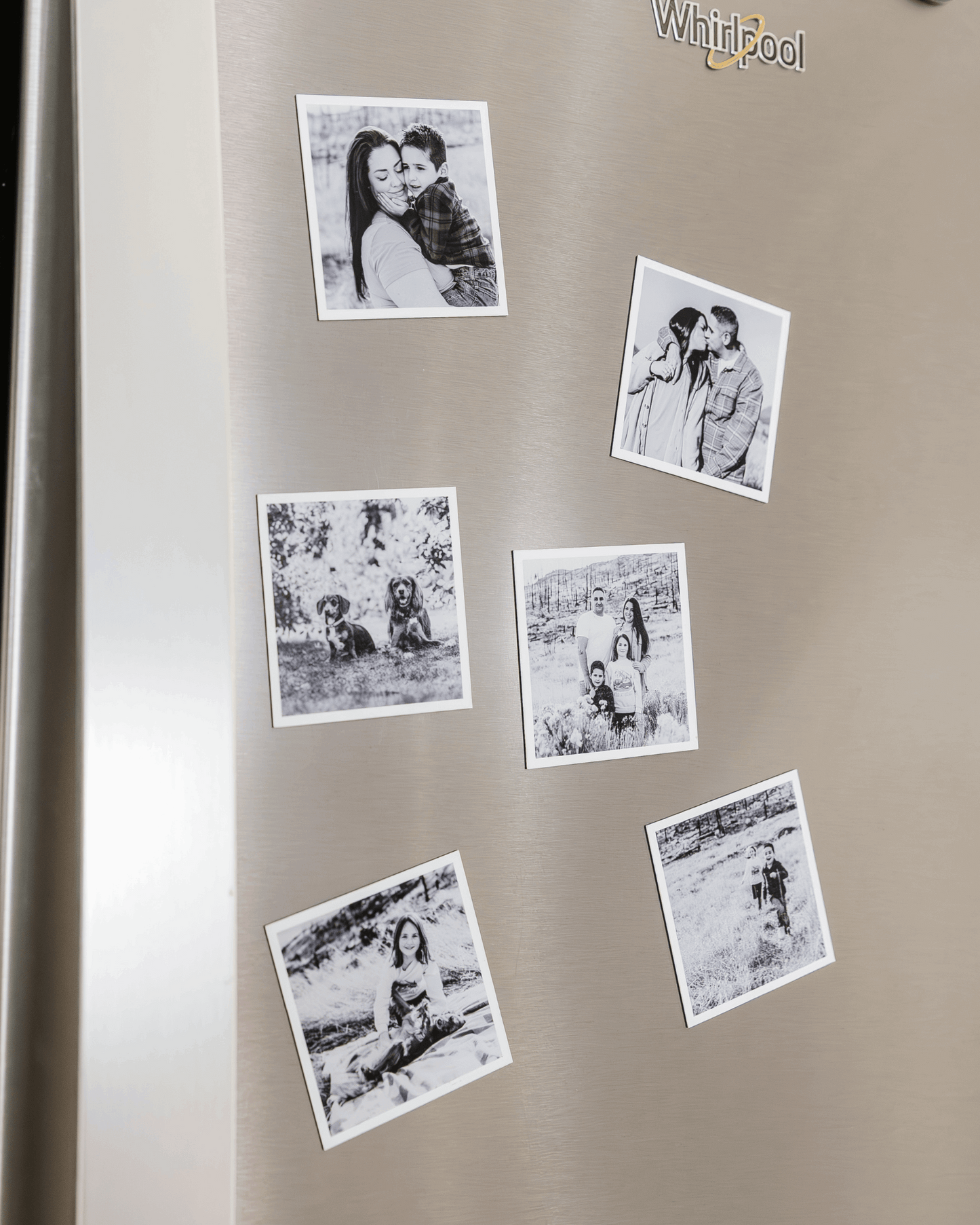 Black and white custom photo magnets displayed on a stainless steel refrigerator door.
