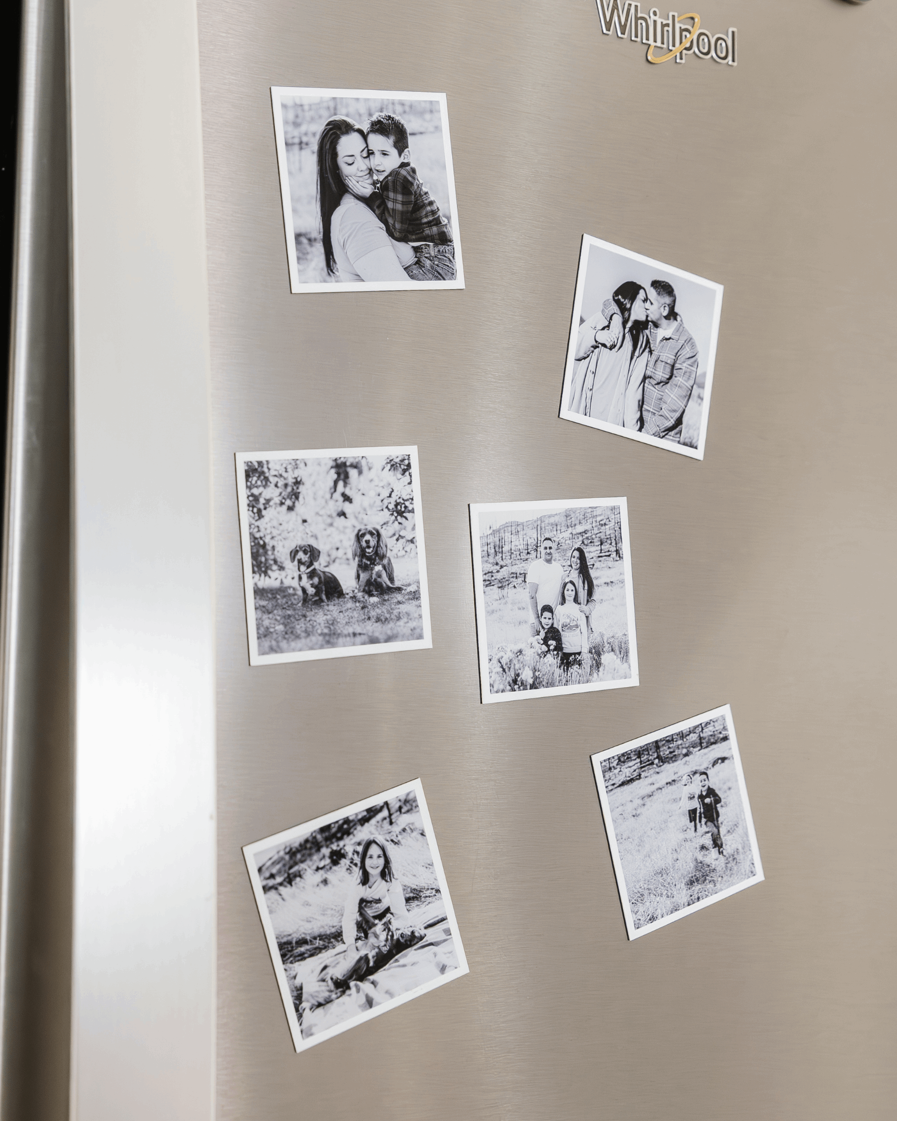 Black and white custom photo magnets displayed on a stainless steel refrigerator door.
