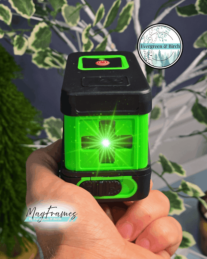Green self-leveling laser level with cross line beams for hanging gallery wall frames, includes tripod and magnetic bracket by Evergreen & Birch.