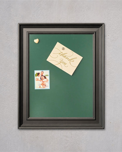 Green magnetic board with a modern black solid wood frame displaying a family photo, thank you note, and decorative heart magnets on a light gray wall.