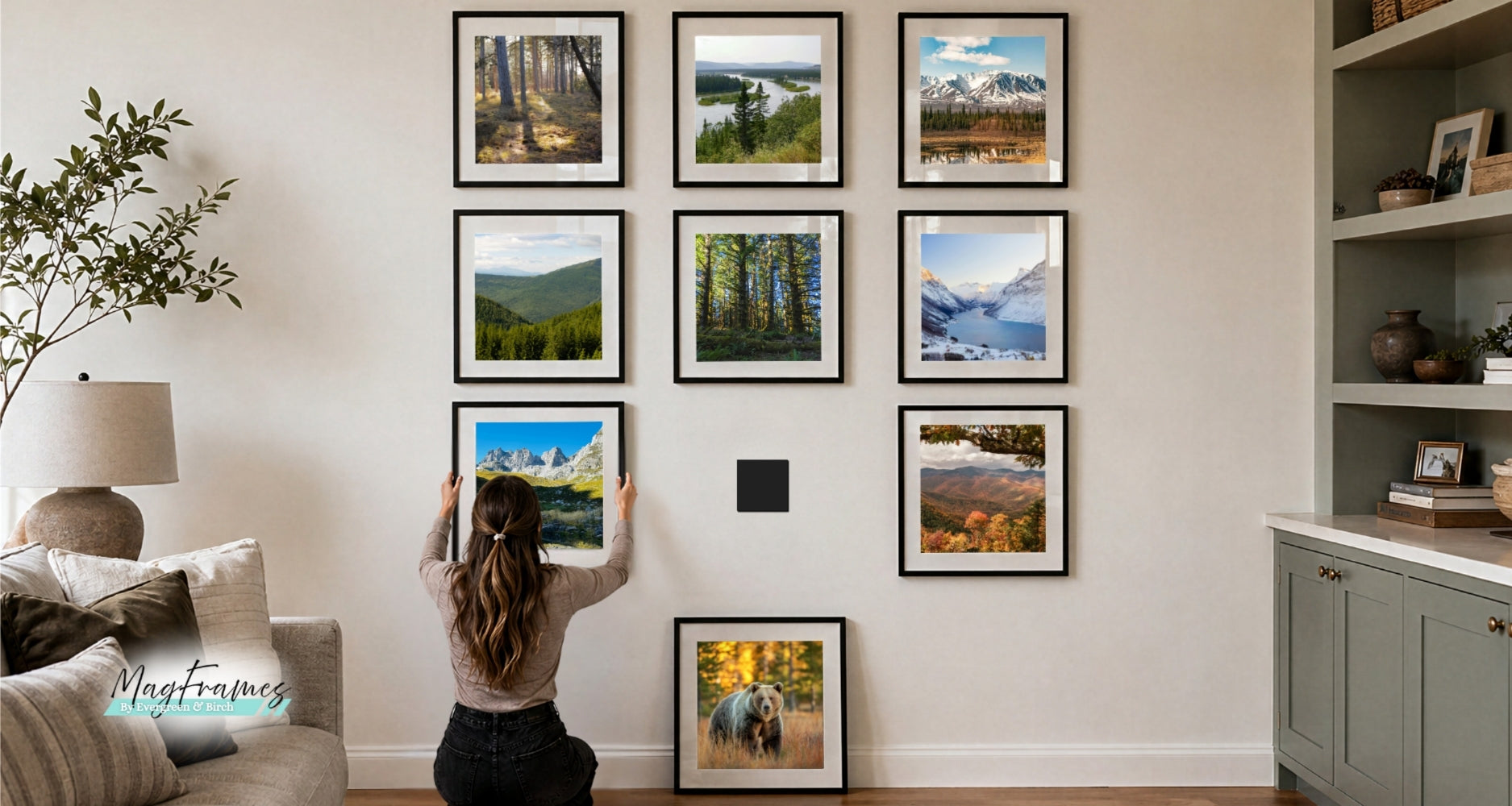 woman arranging magnetic photo frames in a gallery wall layout with landscape prints in a modern living room