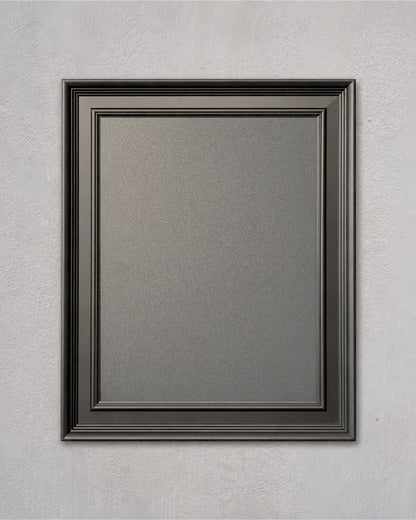 Modern black magnetic board with a solid pine wood frame and powder-coated magnetic steel surface mounted on a light gray textured wall.