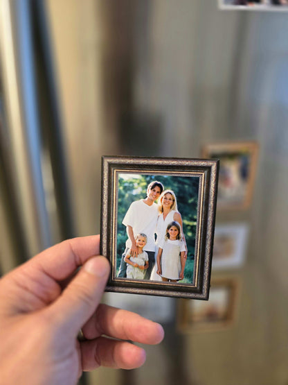 Hand holding personalized vintage frame photo magnet with bronze ornate frame displayed on refrigerator.