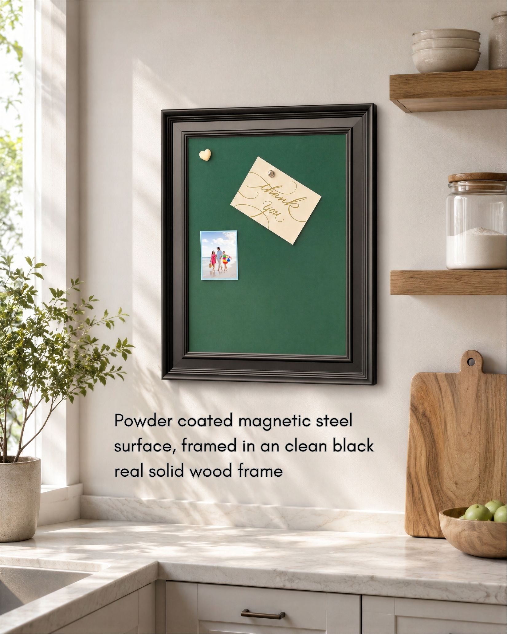 Royal green magnetic board with a modern black solid wood frame mounted in a bright kitchen, featuring pinned notes and photos on a powder-coated magnetic steel surface.